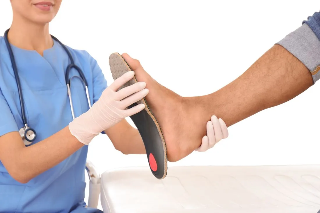 Nurse holding a custom orthotic against a client's foot